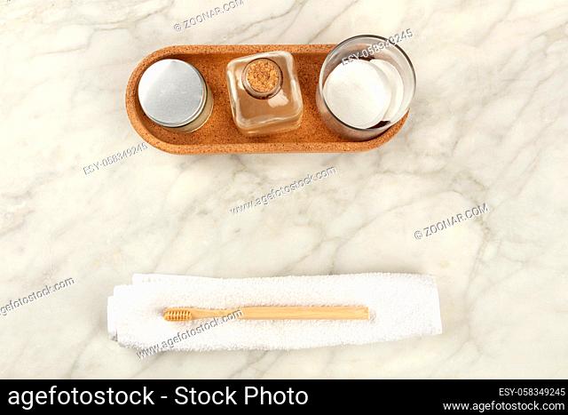 Sustainable toiletries. Homemade lotions, cotton pads, and an organic biodegradable bamboo toothbrush, shot from above on a white marble background with a place...
