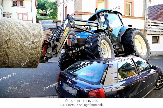 A tractor rests with two wheels on a car in Rothenbuch,  Germany, 10 July 2013. The 82 year-old driver of the tractor that was transporting a bale of hay...