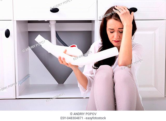 Upset Woman Looking At Damaged Sink Pipe
