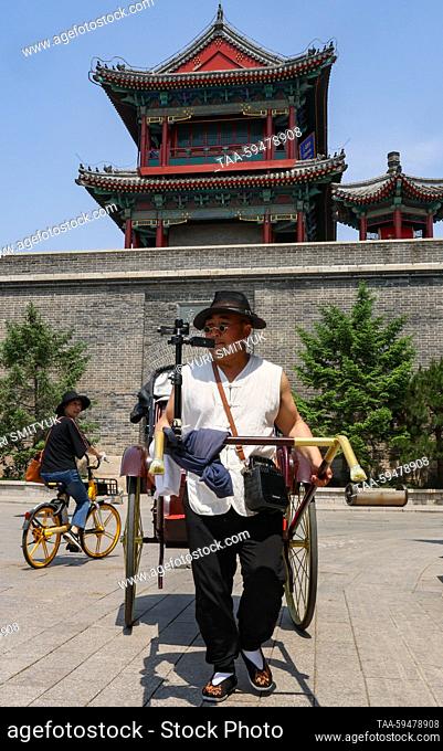 CHINA, HEBEI PROVINCE - MAY 24, 2023: A man pulls a rickshaw across the old town within a fortress in Beidaihe District, Qinhuangdao