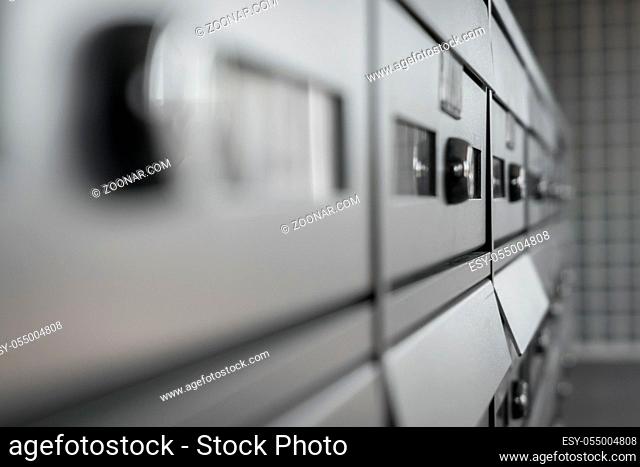 Extreme closeup of modern metallic mailbox in a condominium. Defocused blurry background
