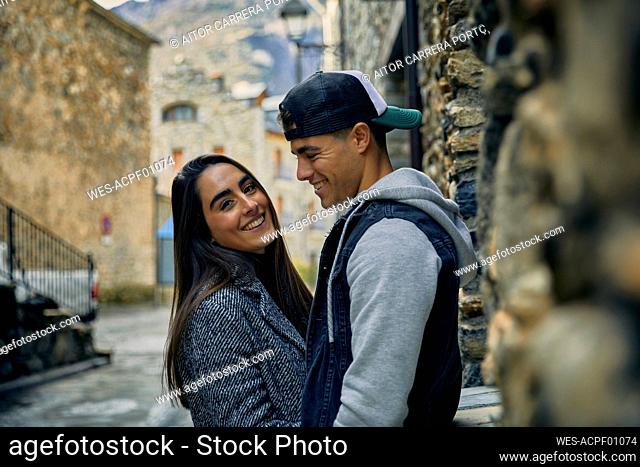 Smiling young man looking at girlfriend while standing in town