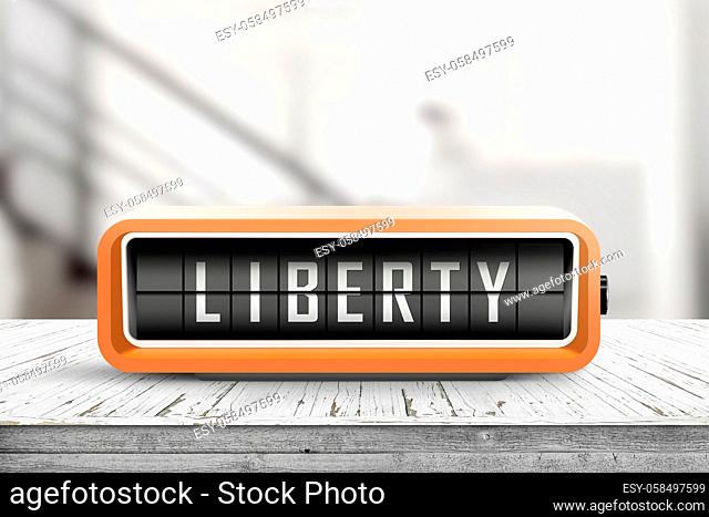 Liberty message on an orange alarm clock in a bright room on a desk