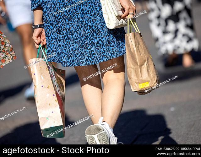 PRODUCTION - 24 June 2023, North Rhine-Westphalia, Cologne: A woman carries two paper bags in Cologne's Schildergasse. Photo: Thomas Banneyer/dpa