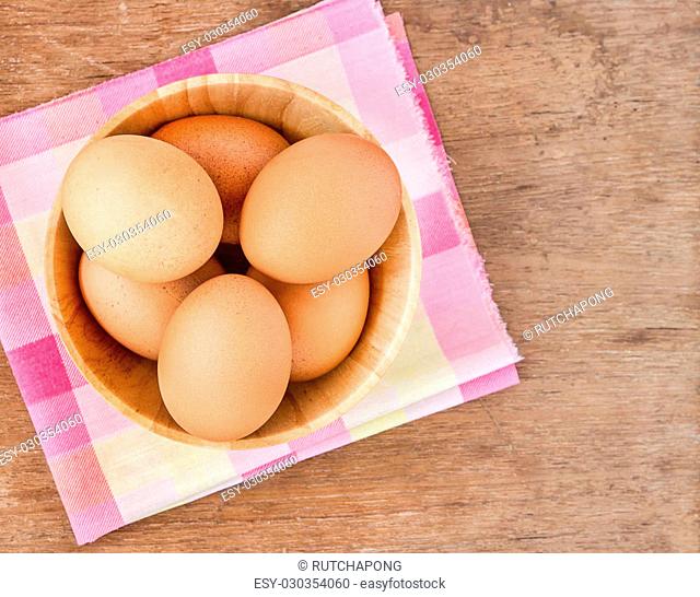 Eggs in a wooden bowl on the table background