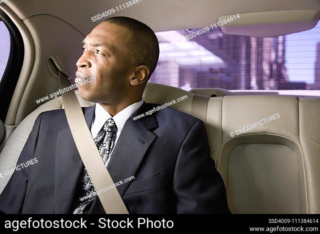 African businessman wearing seatbelt in back seat of car