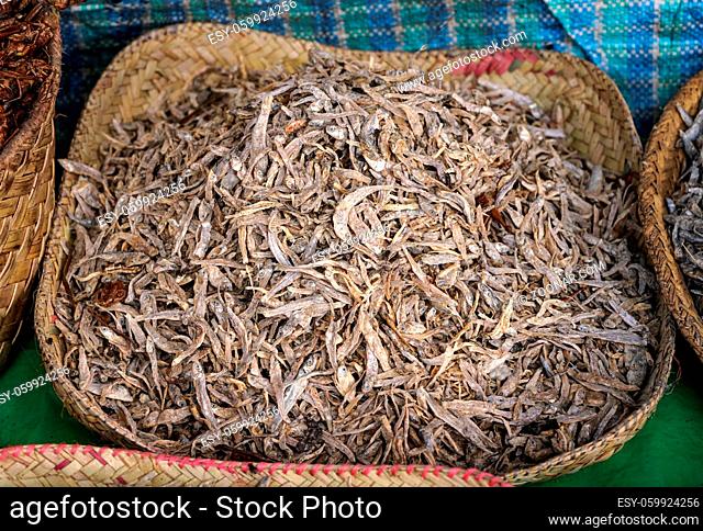 Small dried fish displayed in straw basket on food market at Ranohira, Madagascar, closeup detail