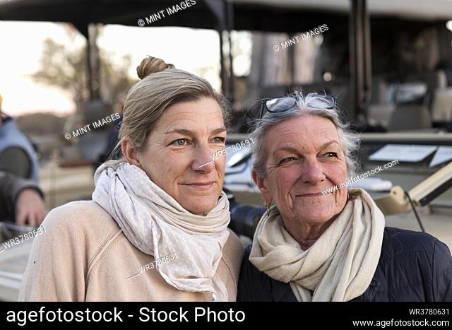 Two women side by side by a safari vehicle, adult woman and her mother, family likeness