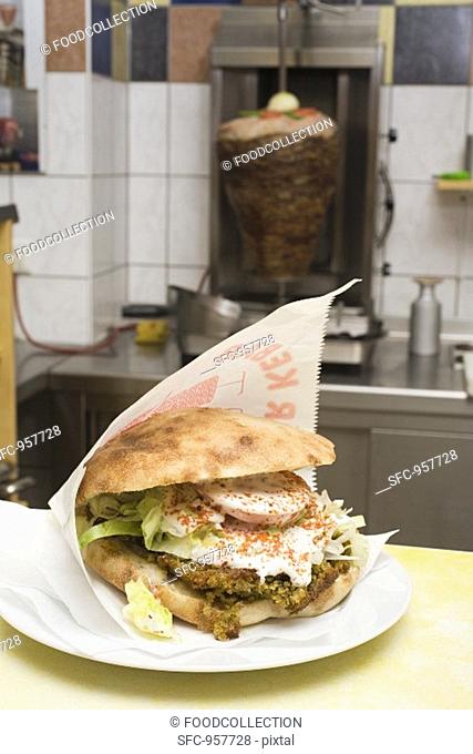 Pita bread with falafel on counter in front of döner grill