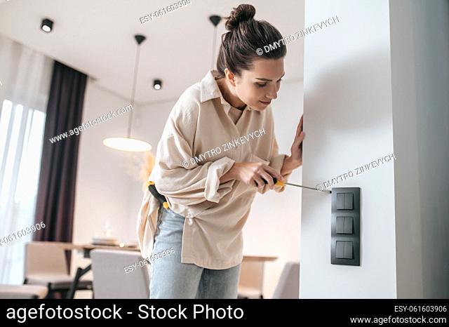 Broken power socket. A young woman checking the power socket and looking involved