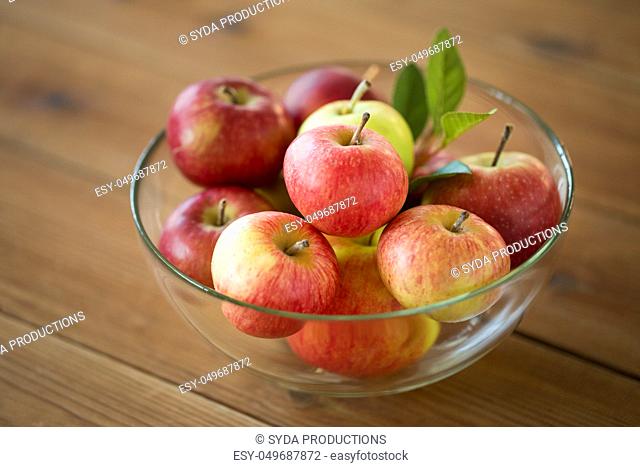 ripe apples in glass bowl on wooden table