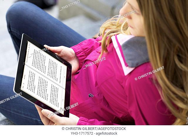 Young caucasian woman reading 'How to Win Friends and Influence People' from iBooks application on an iPad 2