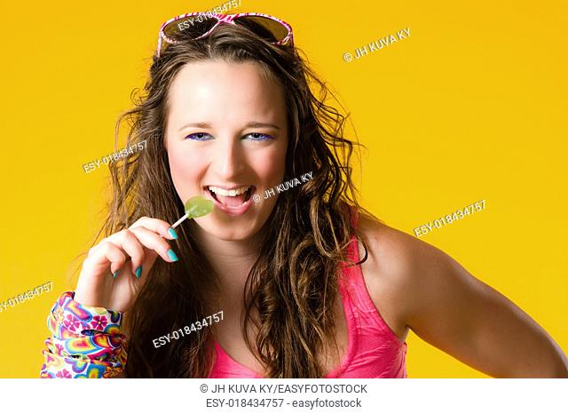 Close-up of beautiful girl and lollipop, make-up, yellow background