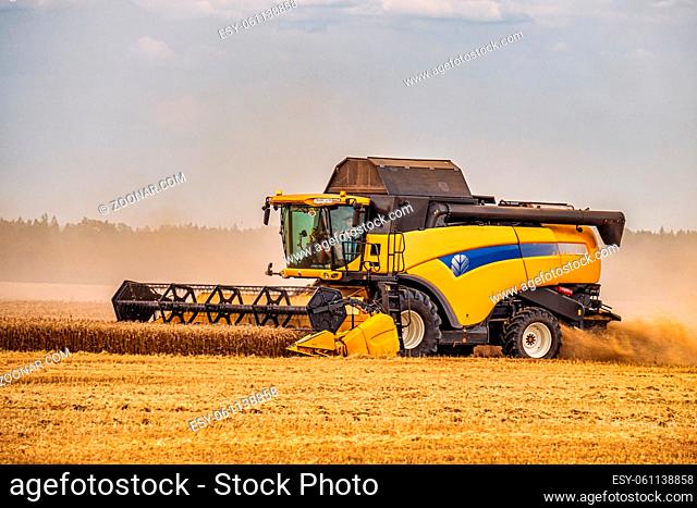 Modern Combine Harvester With a Large Mower in a Wheat Field. Agricultural Seasonal Work