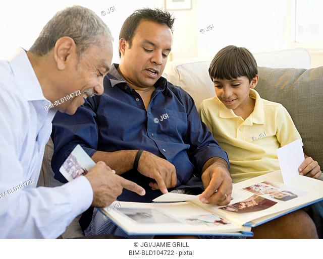 Hispanic grandfather, father and son looking at photo album