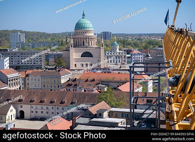 23 April 2020, Brandenburg, Potsdam: The Nikolai Church (M) as well as residential and commercial buildings in the city centre can be seen next to the yellow...