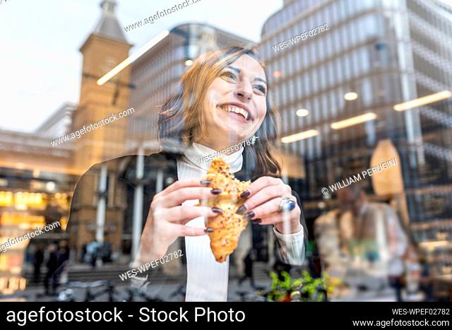 Happy businesswoman having a snack at a cafe in the city
