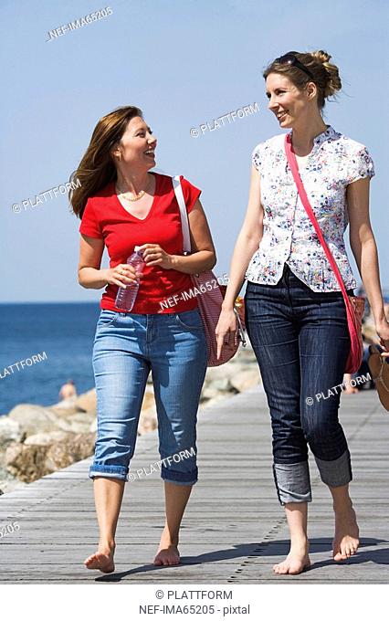 Two women walking on a jetty Malmo Skane Sweden