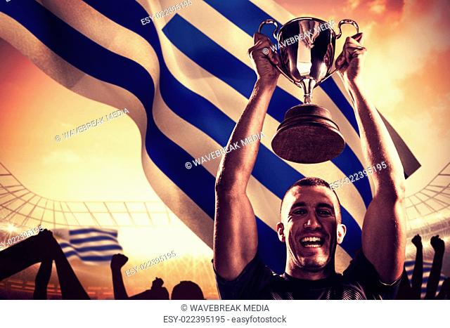 Composite image of portrait of successful rugby player holding trophy