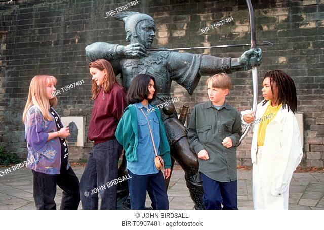 Multiracial group of teenagers standing near Robin Hood statue in grounds of Nottingham castle talking
