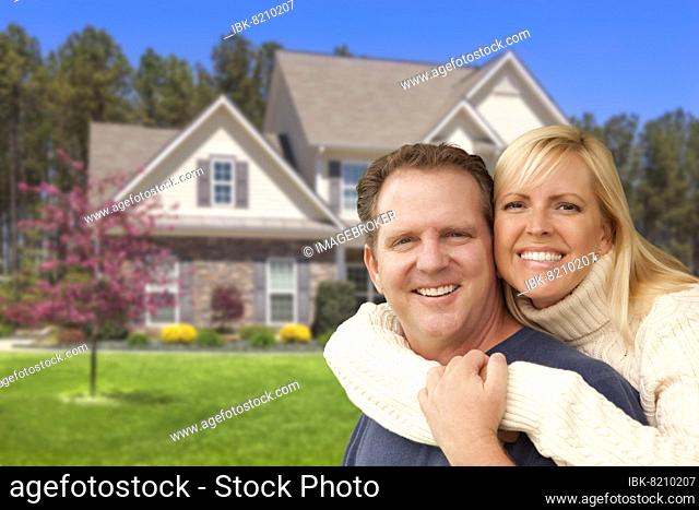 Happy couple hugging in front of beautiful house