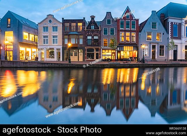 Netherlands, South Holland, Leiden, Row of historical townhouses reflecting in Rhine canal at dusk