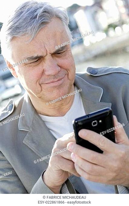 Portrait of senior man using smartphone in town