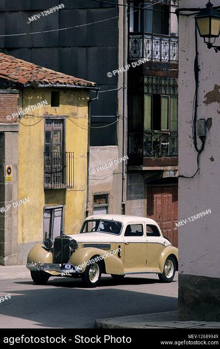 Hispano Suiza car rally - Santander to Madrid. A two-tone saloon drives through a Spanish village