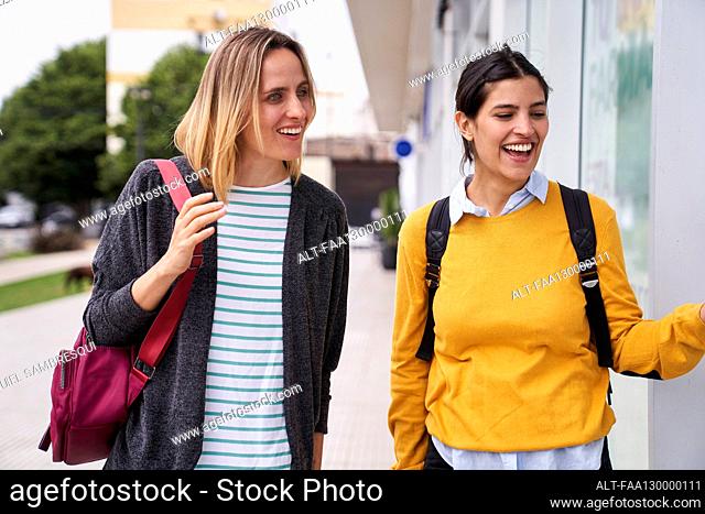 Photo of two friends window shopping outdoors