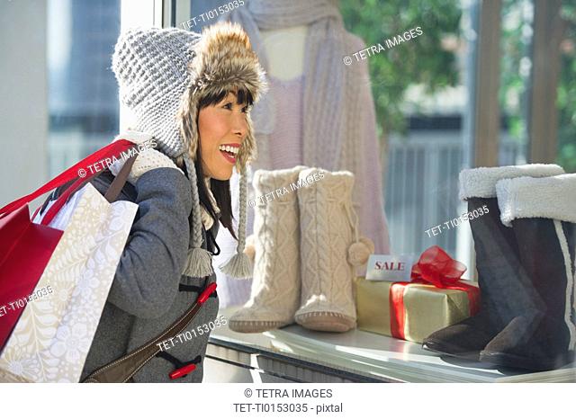 Smiling woman looking at shop display during Christmas shopping