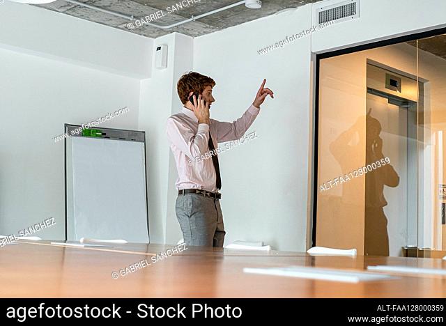 Side view of young man taking on smart phone in office