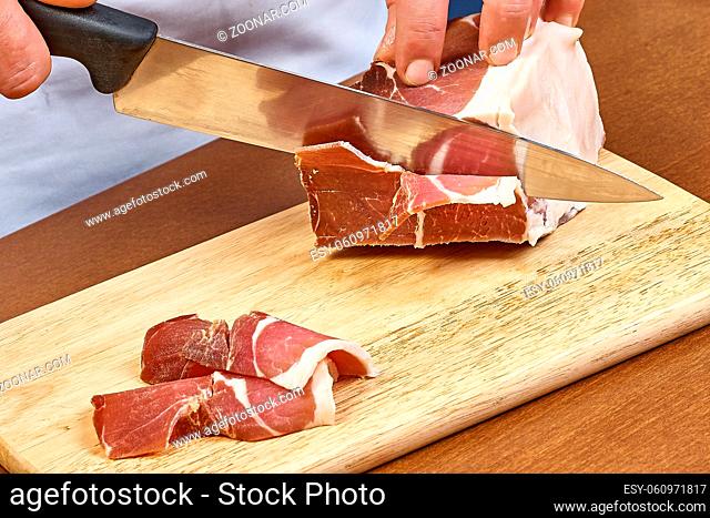 Dry cured ham thinly sliced Closeup on chef hands slices prosciutto Italian delicatessen dishes cooking process