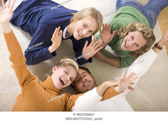 Family lying on floor in living room, smiling, elevated view