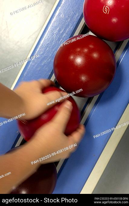 PRODUCTION - 25 January 2023, Thuringia, Auma-Weidatal: A junior player takes a ball at the SV Blau-Weiß Auma clubhouse for a throw on the bowling alley