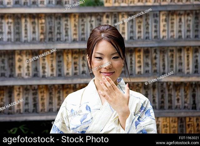 Beautiful young woman in kimono at Japanese prayer boards