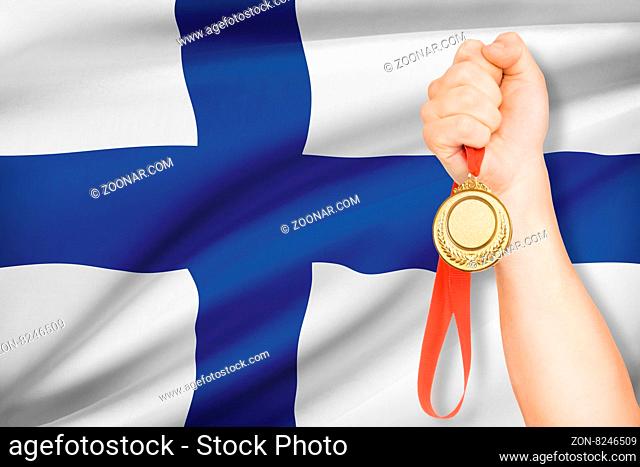 Sportsman holding gold medal with flag on background - Republic of Finland