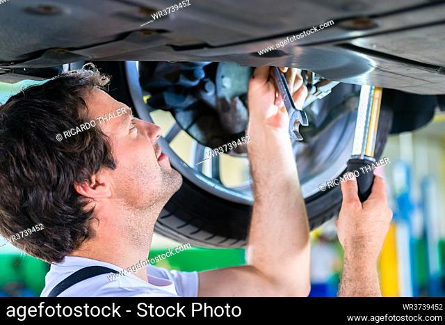 Mechanic working wheel in car service workshop