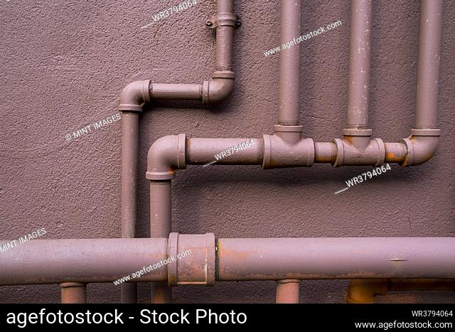 Natural gas utility pipes running along a brown wall, valves and joints