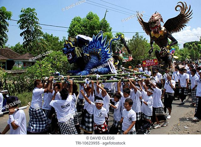 Group of boys and youths lift blue Ogoh Ogoh lion statue on bamboo platform above their heads a second statue follows Hindu celebration of Nyepi the Balinese...