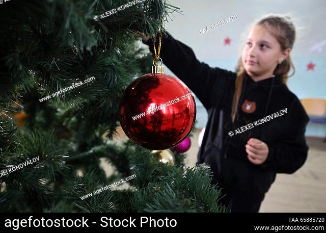 RUSSIA, ZAPOROZHYE REGION - DECEMBER 18, 2023: Kids decorate a Christmas tree at school No 4 in the town of Pologi. The school has 440 students who come from...