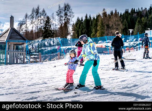 Young happy skier girl learning how to ski with her mom on the green ski zone, Bialka Tatrzanska, Tatry, Poland