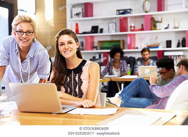 Portrait Of Businesswomen Working On Laptop In Busy Office