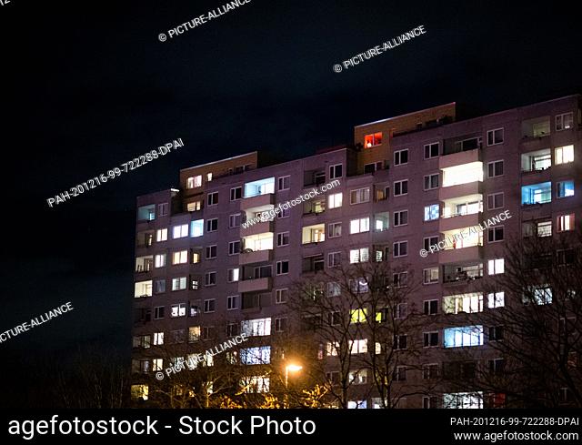 16 December 2020, Lower Saxony, Laatzen: Lights shine from numerous apartments in an apartment building in the evening. A hard lockdown is in place in Germany...