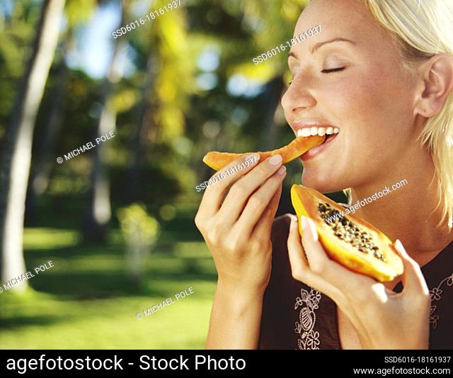 Woman eating Papaya on tropical island