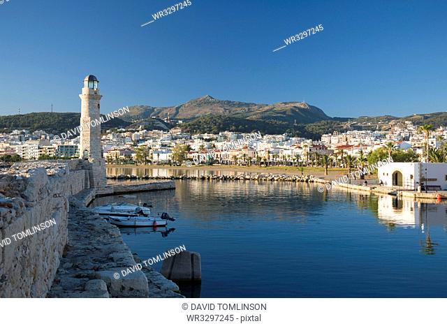 View along sea wall of the Venetian Harbour, 16th century lighthouse prominent, Rethymno (Rethymnon), Crete, Greek Islands, Greece, Europe