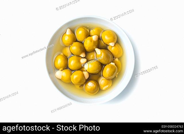 Pitted green olives stuffed with almonds in bowl isolated on white background