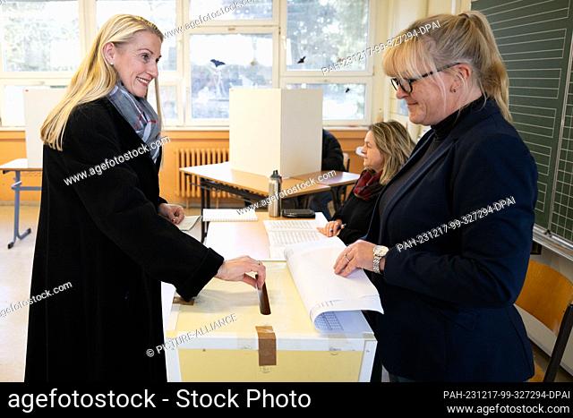 17 December 2023, Saxony, Pirna: Kathrin Dollinger-Knuth (CDU, l), candidate for mayor, casts her ballot in a ballot box at a polling station in an elementary...
