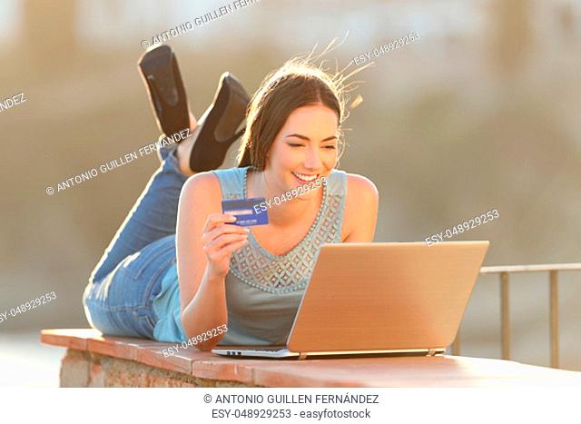 Full body portrait of an online buyer is paying with credit card and laptop