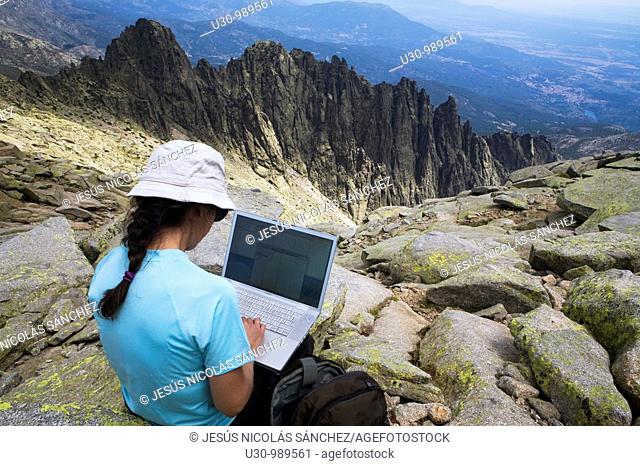 Woman on the summit of La Mira 2 341 m working with a portable computer  Mountains of the Sierra de Gredos National Park  At the bottom of the image the summits...