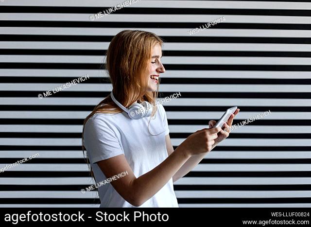 Happy girl enjoying watching tablet PC by striped wall